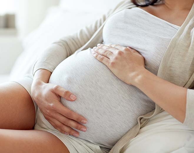 pregnant woman lying down holding belly